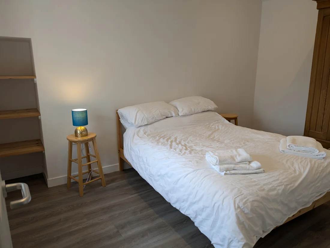 King-size bed with white bedding and a blue bedside lamp in The Cottage