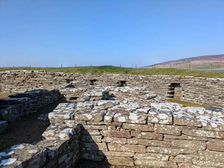 Low stone walls at Cubbie Roo’s Castle on Wyre, with grass and distant hills beyond