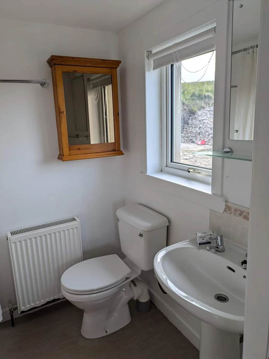 Washbasin, toilet and wooden mirror beside the bathroom window