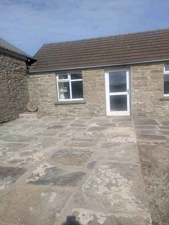 Farmhouse entrance opening onto a stone-paved terrace