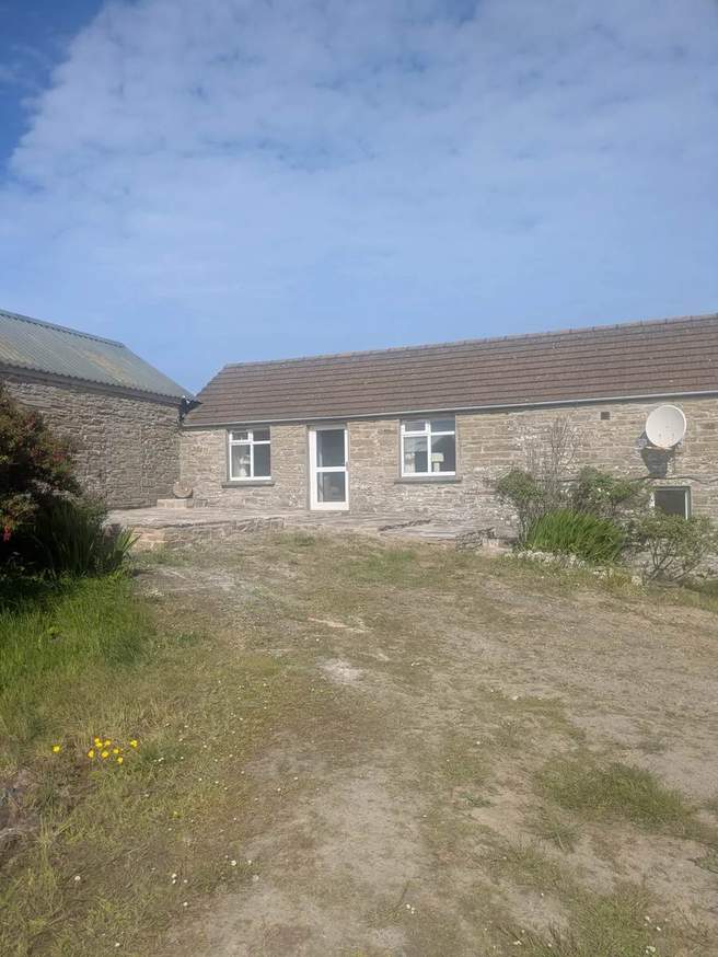 Stone farmhouse frontage with a terrace and planted borders