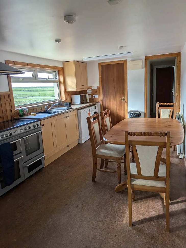 Farmhouse kitchen and dining table beside a window overlooking fields