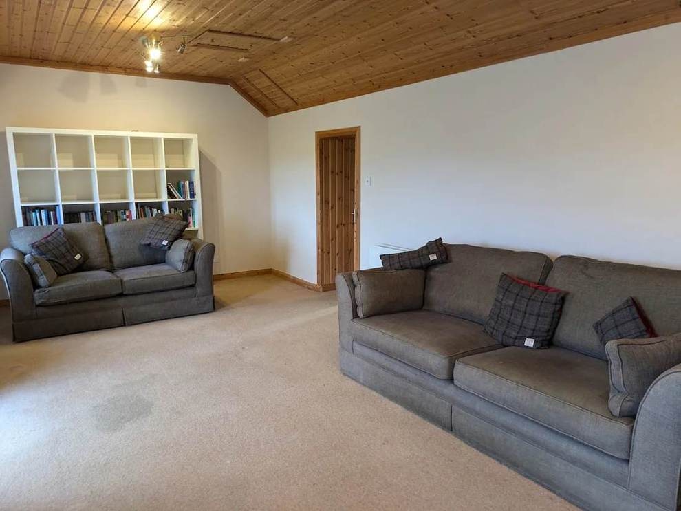 Grey sofas and a bookcase beneath the timber ceiling in The Farmhouse