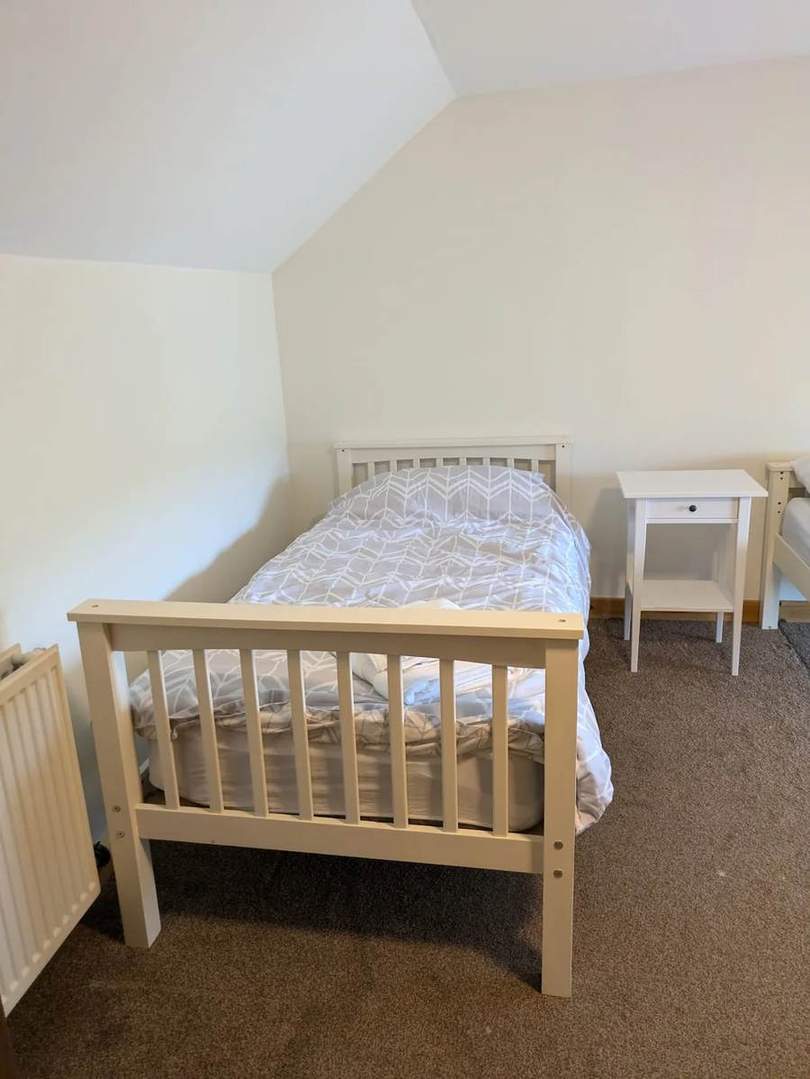 A wooden single bed and bedside table in the twin bedroom